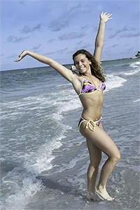 Bikini clad curly haired brunette having fun at the beach
